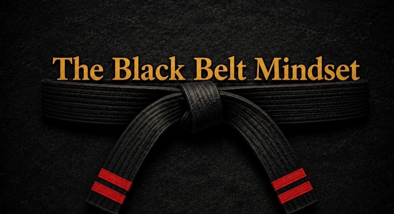 The Black Belt Mindset — a black belt with red stripes on a dark background with gold lettering